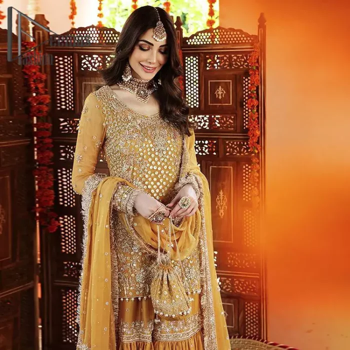 The shirt is the mirror of the mind and the dupatta confesses secrets of the heart. This mustard soft-toned article is highlighted with fascinating golden and antique kora, dabka, and crystal work. The shirt is further enhanced your mayon look with a traditional round neckline and full sleeves. It is paired up with gharara that is prettified with priceless border embroidery. Finish this look with the same colour dupatta that have four-sided embellished lace and Kiran. Further the sequins spray on the dupatta increases the beauty of the article which is every bride's dream.