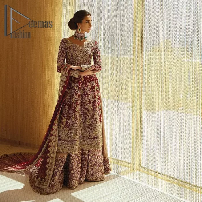 Serving a bold and funky style affair perfect for the big day. Stun in this classic base with contemporary golden adornment serving an elevated style. Detailing of the deep red frock is starting from the delightful and charming golden embroidery which is highlighted with tilla, zardozi, dabka and pearls. The V shape neckline of the frock is as lovely as you can see in the picture. Further, the bottom of the frock is enhanced with the scalloped border as well. It is arranged with the same colour lehenga that is also ornamented with heavy golden embroidery. Finally, end up this outfit with a deep red dupatta which is embellished with a four-sided border and sequins spray all over.