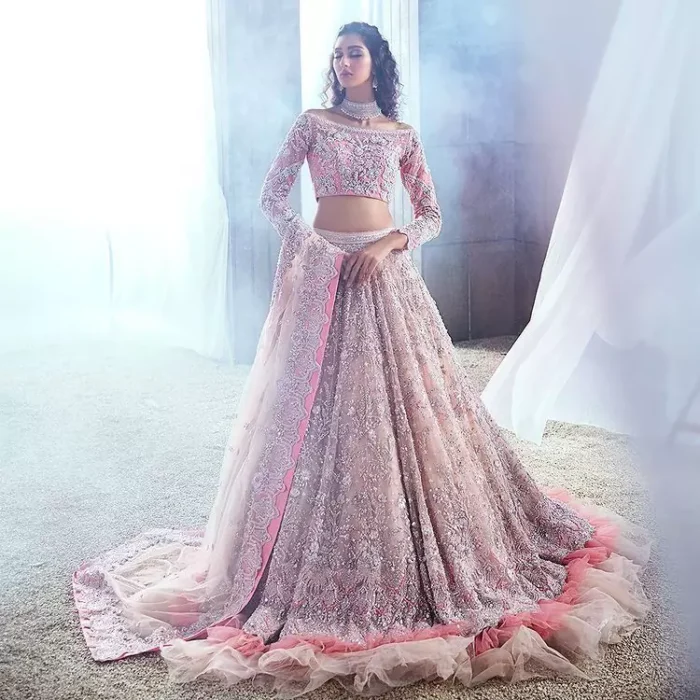 DeemasFashion just defines sophistication and minimal high fashion in terms you desire. Reveal your aura in this tea pink off-shoulder blouse that is beautifully decorated with silver embroidery that involves a kora, dabka, tilla, and crystal look just to grant you mesmerizing look. Further, the full sleeves of the blouse look so admiring on your walima day. It is arranged with a frilled lehenga again which is ornamented with heavy silver embroidery so that you can steal everyone's heart. Finish this article with a tea pink dupatta that is prominent with four-sided border embellishment.