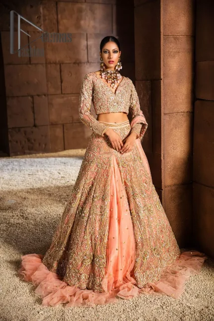 Soft-touch of peach into fresh buds blooming in the garden. This peach article is a perfect pick for your Walima day which is starting with a peach blouse and is heavily ornamented with golden tilla, kora and zardozi work to enhance the fresh look of a bride. In addition to this, it is highlighted with V shape neckline and combined with full sleeves to glow like the flower in the garden. It is paired up with the same colour fluffy lehenga which is enhanced with the bottom frill to fulfil the dream of every girl.  Complete this article with the same colour dupatta which is embellished with four-sided Kiran. 