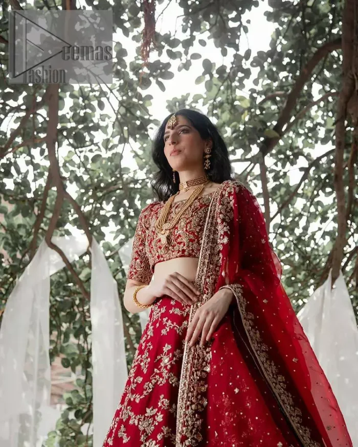 Envelop yourself into the dazzling love affair. Surprise everyone with this deep red article on your Big day. Stating this article with a deep red blouse that is handsomely styled with boat shape neckline. The half sleeves of the blouse just boost the attractiveness of the design.  In addition to this, it is delightfully furnished with golden embroidery which includes kora, dabka and tilla. Brace the blouse with a deep red fluffy lehenga that is again heavily embellished with golden embroidery that increases the beauty of the article. Complete this article with the same colour dupatta which is embellished with a four-sided borders and sequins sprayed all over just to envelop you into the dazzling love affair on your big day. 