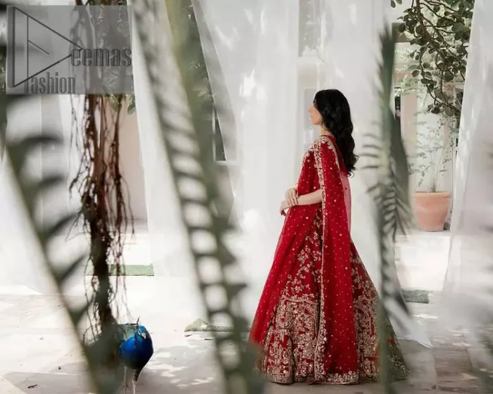 Envelop yourself into the dazzling love affair. Surprise everyone with this deep red article on your Big day. Stating this article with a deep red blouse that is handsomely styled with boat shape neckline. The half sleeves of the blouse just boost the attractiveness of the design.  In addition to this, it is delightfully furnished with golden embroidery which includes kora, dabka and tilla. Brace the blouse with a deep red fluffy lehenga that is again heavily embellished with golden embroidery that increases the beauty of the article. Complete this article with the same colour dupatta which is embellished with a four-sided borders and sequins sprayed all over just to envelop you into the dazzling love affair on your big day. 