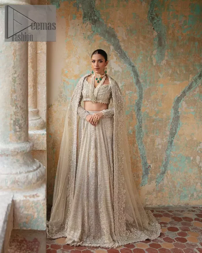 With a touch of Divine. A stunning ivory blouse is laboriously frosted with meticulously detailed hand embellishment with kora, dabka, tilla and pearls all over. The sweetheart neckline of the blouse and full sleeves together gives a so romantic look to any bride. In addition to this, it is systemized with the same colour frilled lehenga which is laden with the same colour embroidery that gives a magical stream of tilla, dabka and pearls. Finish this ivory article with the same colour dupatta that is heavily embellished with four-sided handsome borders and sequins sprayed all over to enhance the feeling of joy. 
