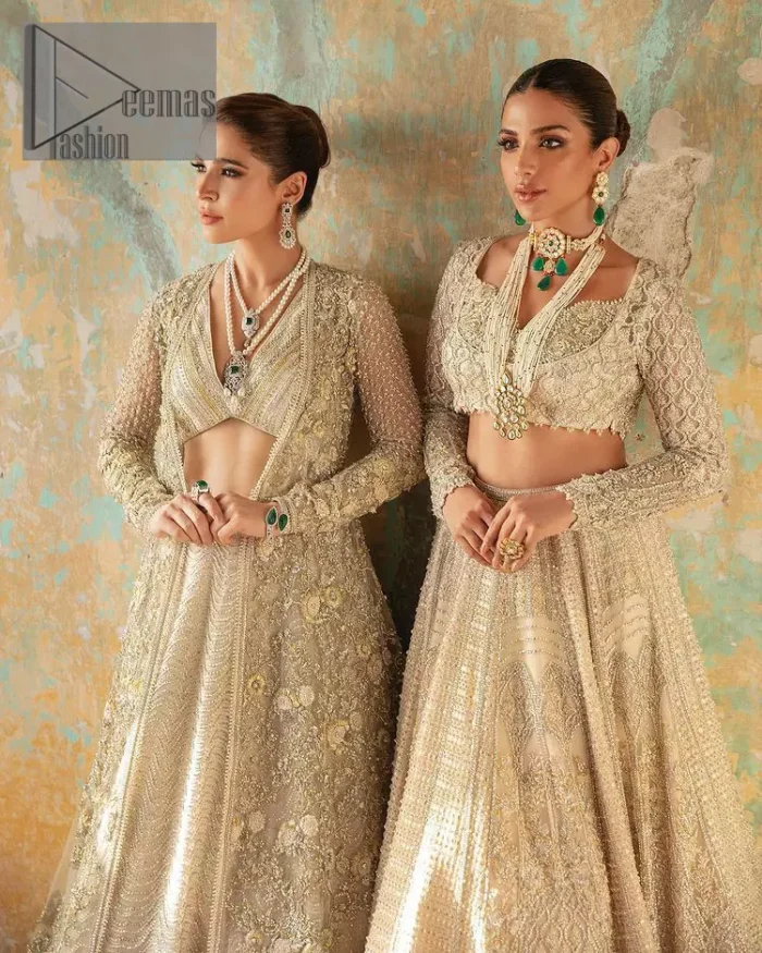 On a magical ivory afternoon, the sun reflects her radiance, the wind mimics her gaze. Starting this ivory article with an attractive and romantic blouse that is beautifully adorned with the same colour embroidery. The V shape neckline of the blouse adds a lovely feeling as well. In addition to this, it is organized with the same colour front open gown that is heavily adorned with tilla, dabka, kora and pearls embroidery. It is highlighted with full sleeves style that shows the uniqueness of the article. Paired up with the same colour lehenga to boost up the walima day of every bride. Complete this article with an ivory dupatta that is embellished with four-sided borders and sequins spray and tiny floral motifs spread all over. 