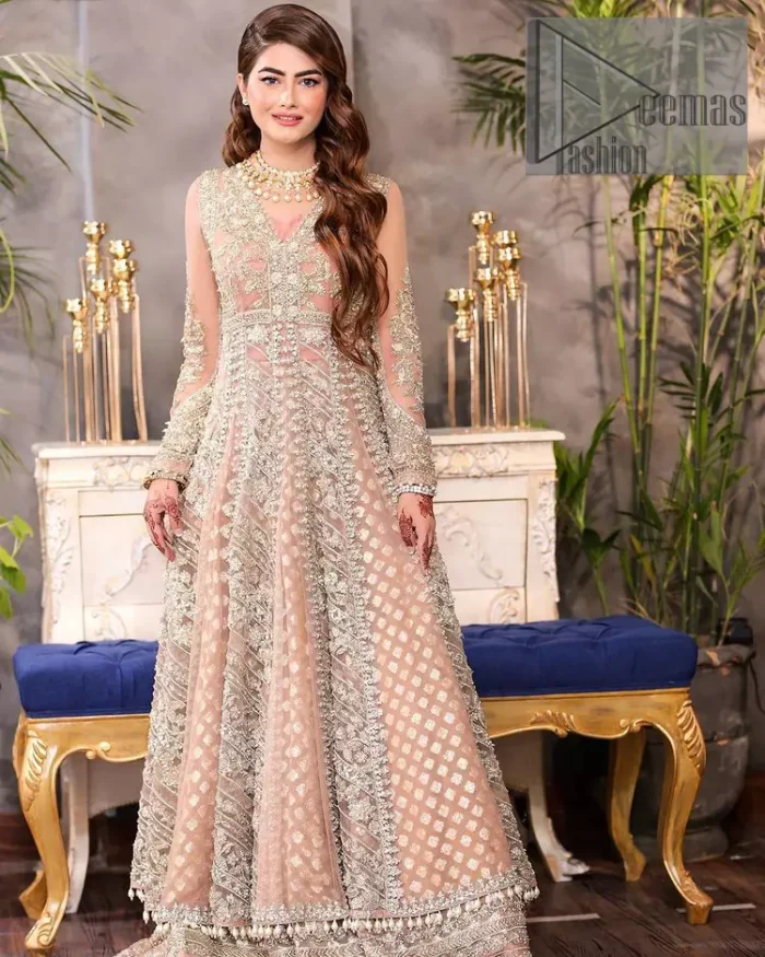 Its lustrous, lush and lavish in every sense of the word with its dazzling nude peach base. The nude peach multiple panel frock is amazing for your walima day. The V shape neckline is heavily embellished with embroidery. Further, this aesthetic nude peach frock is enhanced with silver pearls, tilla and dabka work. It is prominent with full sleeves that give a soothing effect to this article. It is complete in its pleasing loudness with an equal nude peach sharara that is adorned with silver embroidery just to fulfil the fairy dream of every bride. 