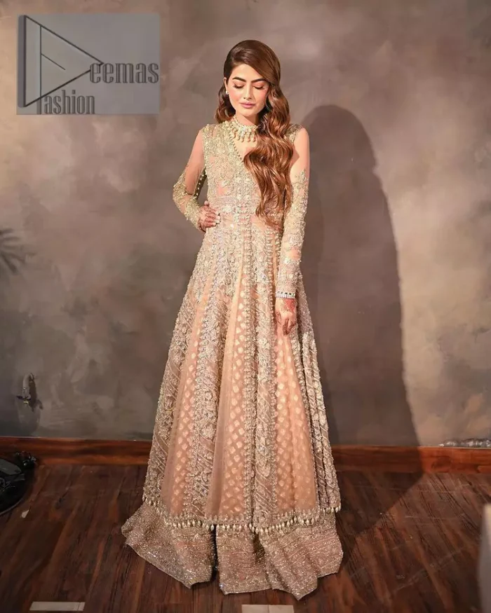 Its lustrous, lush and lavish in every sense of the word with its dazzling nude peach base. The nude peach multiple panel frock is amazing for your walima day. The V shape neckline is heavily embellished with embroidery. Further, this aesthetic nude peach frock is enhanced with silver pearls, tilla and dabka work. It is prominent with full sleeves that give a soothing effect to this article. It is complete in its pleasing loudness with an equal nude peach sharara that is adorned with silver embroidery just to fulfil the fairy dream of every bride. 