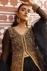 With the timeless charm of black so back on traditional flavour to steal everyone's heart. Introducing the black jacket that is the epitome of splendour with delicate details beautifully decorated with golden colour. The bodice of the jacket is enhanced with stunning embroidery with worked finishing of tilla, kora, dabka and zardozi. The addition of simple sleeves with V shape neckline can be done to make this super traditional. To complete this traditional jacket, a crushed sharara is added to give you an amazing look at any formal event. Complete this black outfit with a black dupatta in a plain style that is perfect for any intimate eveningÂ