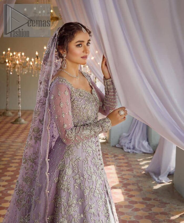 Bold instruments on a bright canvas make a true fashion statement. Introducing a lilac outfit for your Walima day to boost up your day. The front open gown in lilac colour looks as amazing as any bride's dream. It is encapsulated with silver embroidery which contains crystal, tilla, dabka, kora and sequins spray all over. In addition to this, it is highlighted with a sweetheart neckline to enhance the beauty of the gown when combined with full sleeves. It is systemized with silver barcode sharara finished with silver border embroidery that enhances the look of the bride during the day as well as night events. Complete this lilac article with a dupatta which is ornamented with four-sided borders and sequins sprayed all over. 