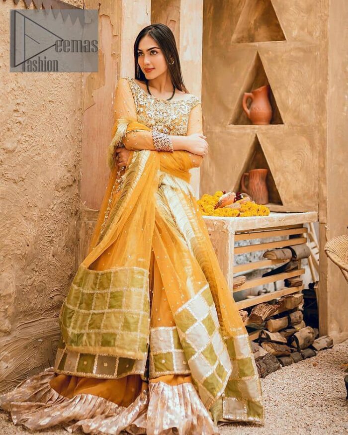 Mustard is just associated and boosts your Mehandi.  Presenting a dreamy mustard frock with a heavily embroidered bodice on a silver base. The bodice is further enhanced with handwork that includes crystal, tilla, kora and dabka work. Furthermore, the boat shape neckline and tiny work on full sleeves have the super style just to boost your day. The bottom is decorated with artistic embroidery that is adding glam to it. The Mehandi look is completed with an artistically crafted frilled lehenga which frill borders displaying the traditional hint of charm. It is coordinated with a dupatta in the same colour that is embellished with four-sided borders as well. 