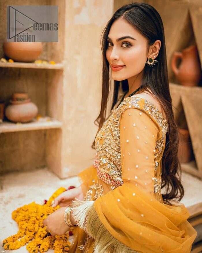 Mustard is just associated and boosts your Mehandi.  Presenting a dreamy mustard frock with a heavily embroidered bodice on a silver base. The bodice is further enhanced with handwork that includes crystal, tilla, kora and dabka work. Furthermore, the boat shape neckline and tiny work on full sleeves have the super style just to boost your day. The bottom is decorated with artistic embroidery that is adding glam to it. The Mehandi look is completed with an artistically crafted frilled lehenga which frill borders displaying the traditional hint of charm. It is coordinated with a dupatta in the same colour that is embellished with four-sided borders as well. 