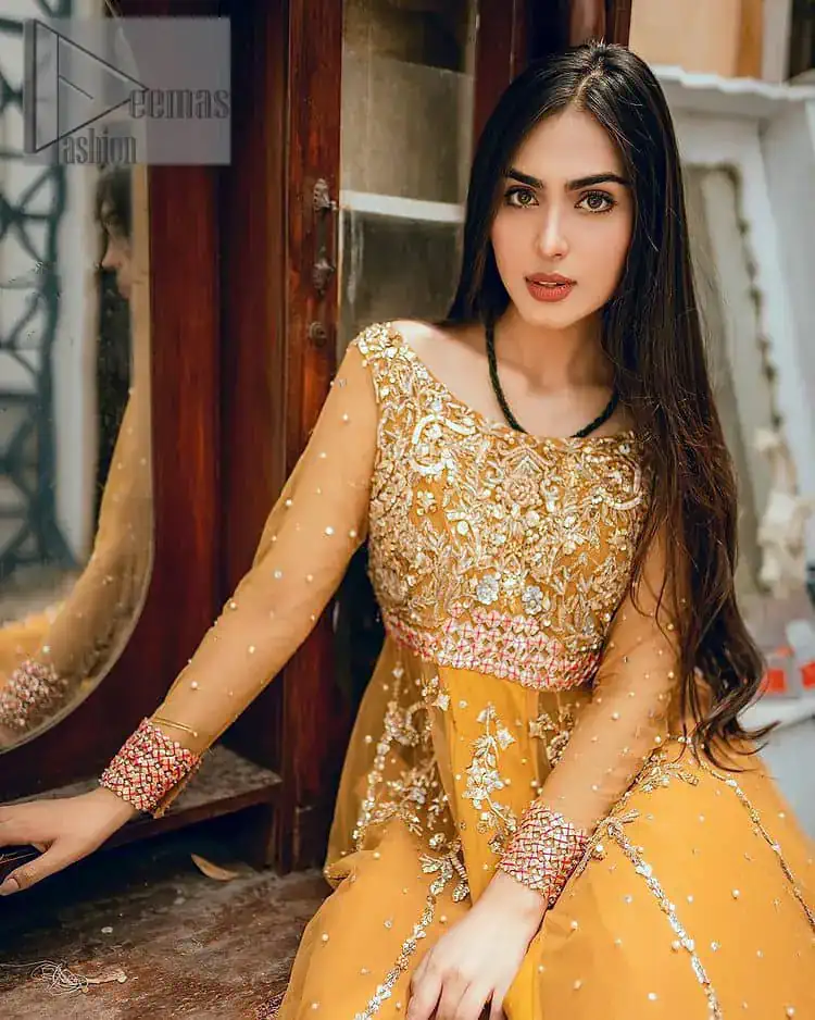 Mustard is just associated and boosts your Mehandi.  Presenting a dreamy mustard frock with a heavily embroidered bodice on a silver base. The bodice is further enhanced with handwork that includes crystal, tilla, kora and dabka work. Furthermore, the boat shape neckline and tiny work on full sleeves have the super style just to boost your day. The bottom is decorated with artistic embroidery that is adding glam to it. The Mehandi look is completed with an artistically crafted frilled lehenga which frill borders displaying the traditional hint of charm. It is coordinated with a dupatta in the same colour that is embellished with four-sided borders as well. 