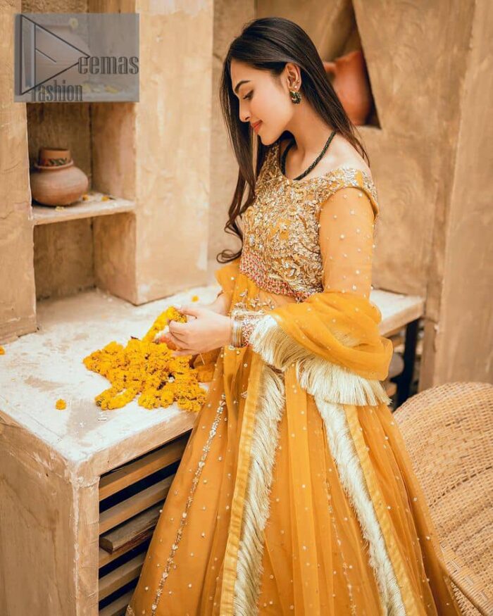 Mustard is just associated and boosts your Mehandi.  Presenting a dreamy mustard frock with a heavily embroidered bodice on a silver base. The bodice is further enhanced with handwork that includes crystal, tilla, kora and dabka work. Furthermore, the boat shape neckline and tiny work on full sleeves have the super style just to boost your day. The bottom is decorated with artistic embroidery that is adding glam to it. The Mehandi look is completed with an artistically crafted frilled lehenga which frill borders displaying the traditional hint of charm. It is coordinated with a dupatta in the same colour that is embellished with four-sided borders as well. 