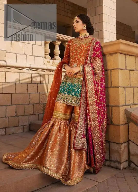 Be a happy and charming bride just like orange is a happy colour. DeemasFashion presents you with an orange short shit that is laboriously embellished with golden embroidery. The base of embroidery starts from the boat shape neckline of the shirt that giving a fully artistic look. In addition to this, it is enhanced with tilla, dabka, kora and Kundan work. The half sleeves of the dhirt also enhance the beauty of the handwork. It is coordinated with orange gharara that is perfect for entimate evening of your Mehandi. Finish this outfit with Pink dupatta that is adorned with ravishing details, the embellished borders represent the craftsmanship of DeemasFashion.