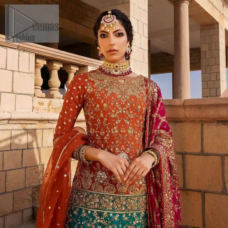 Be a happy and charming bride just like orange is a happy colour. DeemasFashion presents you with an orange short shit that is laboriously embellished with golden embroidery. The base of embroidery starts from the boat shape neckline of the shirt that giving a fully artistic look. In addition to this, it is enhanced with tilla, dabka, kora and Kundan work. The half sleeves of the dhirt also enhance the beauty of the handwork. It is coordinated with orange gharara that is perfect for entimate evening of your Mehandi. Finish this outfit with Pink dupatta that is adorned with ravishing details, the embellished borders represent the craftsmanship of DeemasFashion.