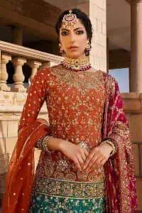 Be a happy and charming bride just like orange is a happy colour. DeemasFashion presents you with an orange short shit that is laboriously embellished with golden embroidery. The base of embroidery starts from the boat shape neckline of the shirt that giving a fully artistic look. In addition to this, it is enhanced with tilla, dabka, kora and Kundan work. The half sleeves of the dhirt also enhance the beauty of the handwork. It is coordinated with orange gharara that is perfect for entimate evening of your Mehandi. Finish this outfit with Pink dupatta that is adorned with ravishing details, the embellished borders represent the craftsmanship of DeemasFashion.