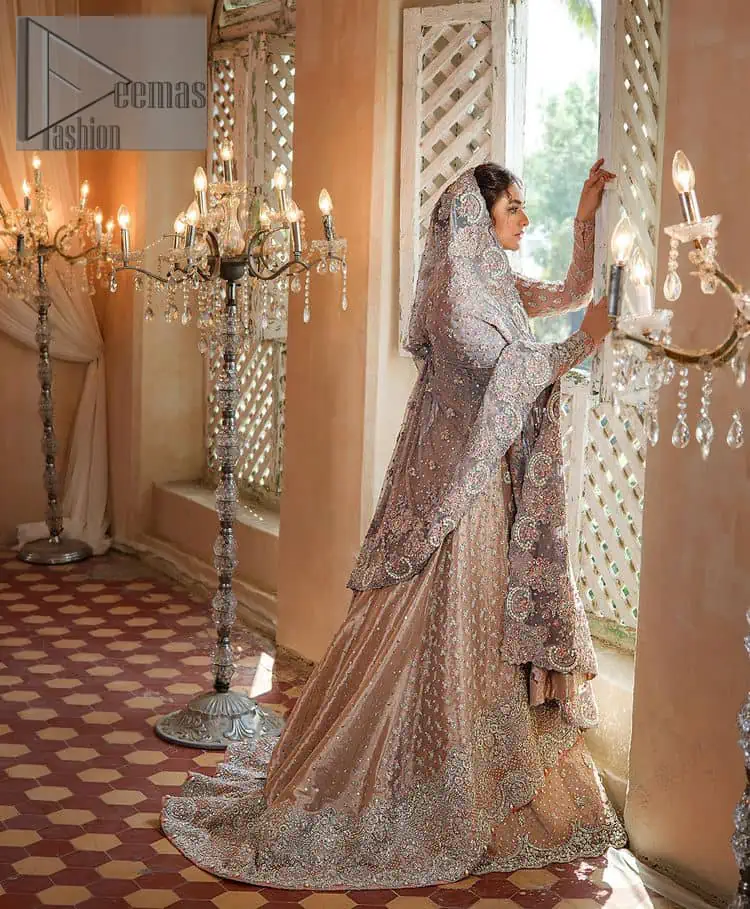 Amplify your style on your Walima day in this stunning light color. DeemasFashion presents the super handsome rose gold outfit for you. First of all, which includes back train maxi in the rose gold colour. It is prominent with the silver embroidery that is encrusted with pearls, silver crystals, kora, dabka and sequins all over highlighting floral patterns. Further, it is emphasized with boat shape neckline and full sleeves that increase the opulent statement of the outfit. It is organized with rose gold sharara which is also embellished with heavy silver embroidery to make your day super dazzling. Finish this look with the rose gold dupatta that is accentuated with sequins and booti spray all over and adorned with a four-sided matha Patti border.