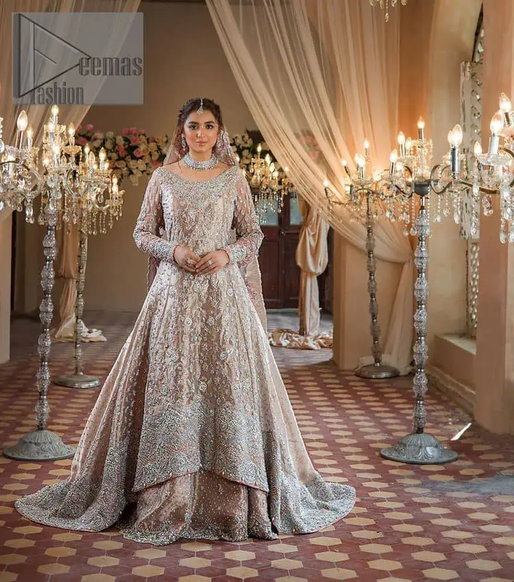 Amplify your style on your Walima day in this stunning light color. DeemasFashion presents the super handsome rose gold outfit for you. First of all, which includes back train maxi in the rose gold colour. It is prominent with the silver embroidery that is encrusted with pearls, silver crystals, kora, dabka and sequins all over highlighting floral patterns. Further, it is emphasized with boat shape neckline and full sleeves that increase the opulent statement of the outfit. It is organized with rose gold sharara which is also embellished with heavy silver embroidery to make your day super dazzling. Finish this look with the rose gold dupatta that is accentuated with sequins and booti spray all over and adorned with a four-sided matha Patti border.