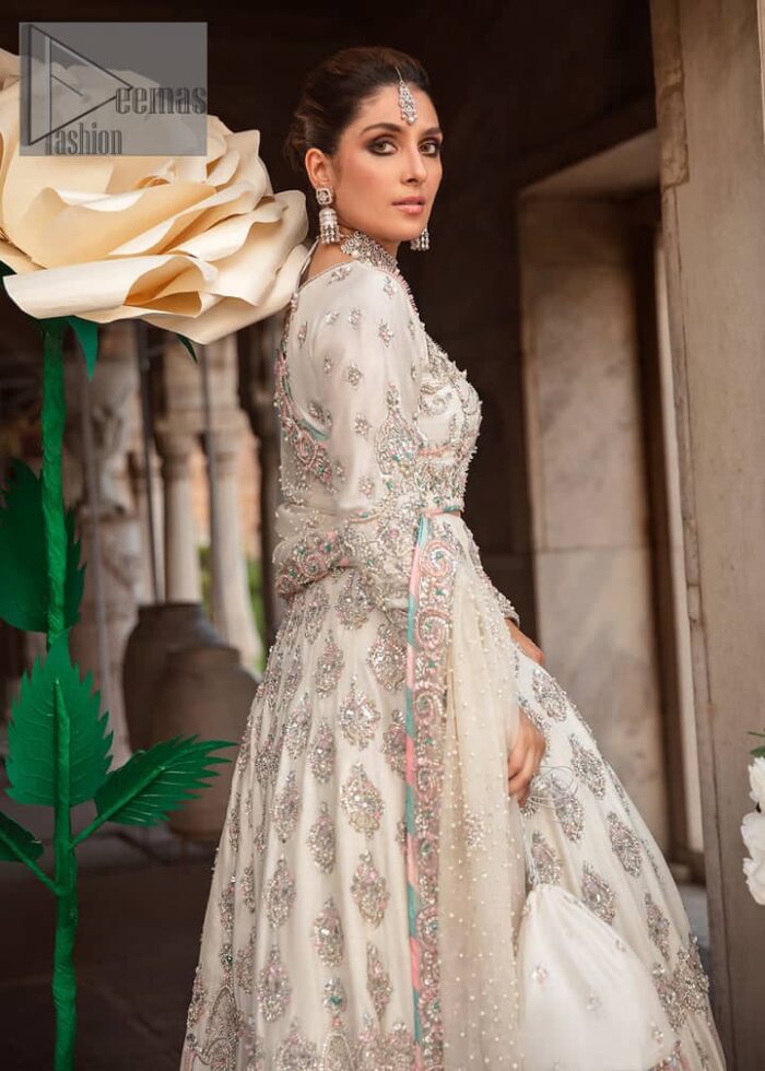 Ivory is effortlessly snappy and fun with the essence of pop. Introducing the Walima outfit for the happiest bride. Starting the outfit with an astonishing blouse having golden embroidery which includes kora, dabka, tilla and Kundan to make this outfit a unique piece of fun. Further, it is enhanced with boat shape neckline with intimate full sleeves. It is beautifully organized with a can-can lehenga in the same colour to embrace the magic of love. The floral embroidery on the lehenga gives a super aesthetic feeling to the outfit. Finish this look with the handsome dupatta in the same hue having a four-sided embellished border and sequins sprayed all over to show the essence of pop.