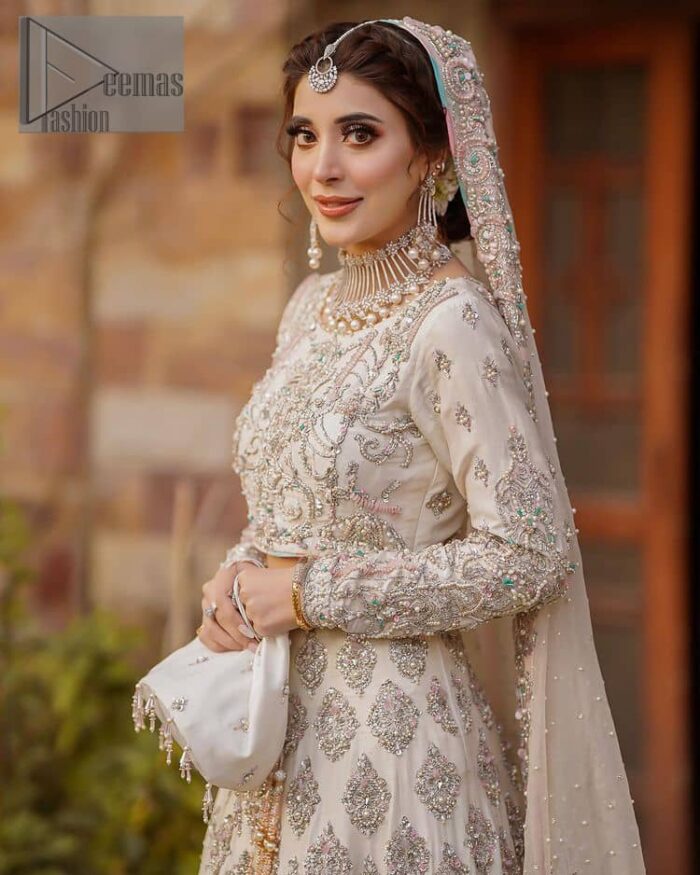 Ivory is effortlessly snappy and fun with the essence of pop. Introducing the Walima outfit for the happiest bride. Starting the outfit with an astonishing blouse having golden embroidery which includes kora, dabka, tilla and Kundan to make this outfit a unique piece of fun. Further, it is enhanced with boat shape neckline with intimate full sleeves. It is beautifully organized with a can-can lehenga in the same colour to embrace the magic of love. The floral embroidery on the lehenga gives a super aesthetic feeling to the outfit. Finish this look with the handsome dupatta in the same hue having a four-sided embellished border and sequins sprayed all over to show the essence of pop.