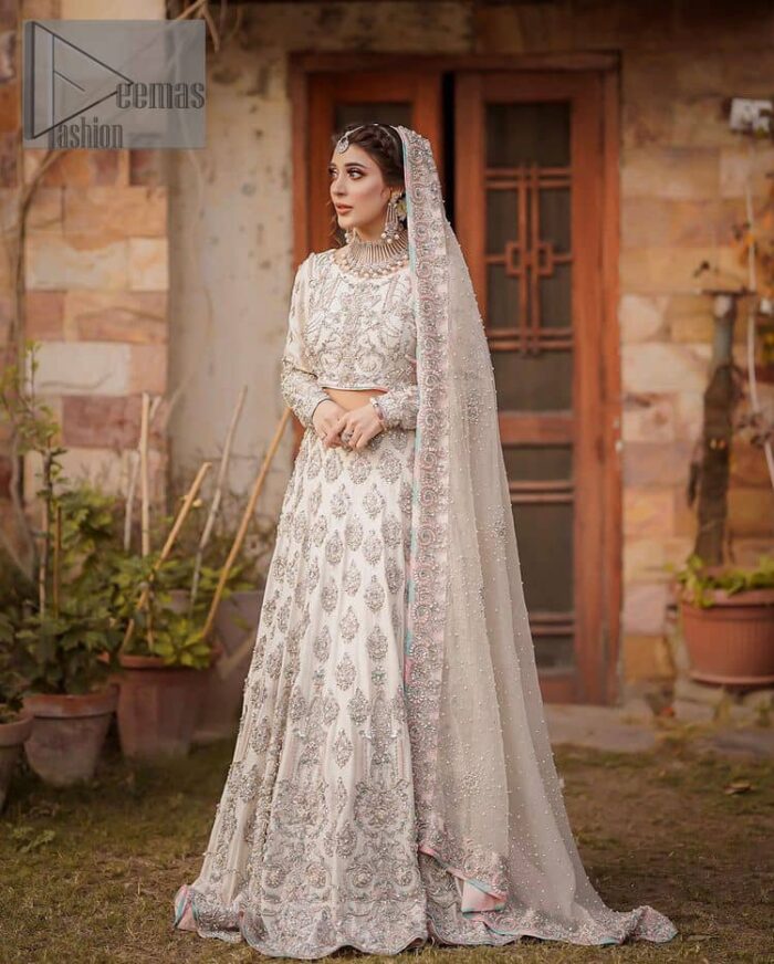 Ivory is effortlessly snappy and fun with the essence of pop. Introducing the Walima outfit for the happiest bride. Starting the outfit with an astonishing blouse having golden embroidery which includes kora, dabka, tilla and Kundan to make this outfit a unique piece of fun. Further, it is enhanced with boat shape neckline with intimate full sleeves. It is beautifully organized with a can-can lehenga in the same colour to embrace the magic of love. The floral embroidery on the lehenga gives a super aesthetic feeling to the outfit. Finish this look with the handsome dupatta in the same hue having a four-sided embellished border and sequins sprayed all over to show the essence of pop.