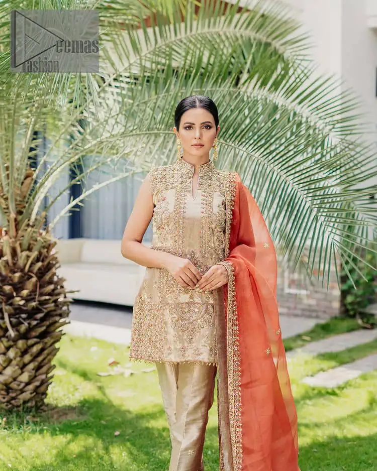 Envelop yourself into a dazzling love affair. The unique article in ivory colour just highlighted you at any event. The short shirt of the article is handsomely decorated with golden embroidery which includes kora, dabka, tilla, Kundan and Sitara work to make your event blazing and dazzling. It is enhanced with a collared neckline to make this outfit more formal when come with a sleeveless style. Further, it is coordinated with pant which is embellished with golden embroidery. Last but not least piece the dupatta comes in rust colour having four-sided embellished borders to encapsulate you in stars.