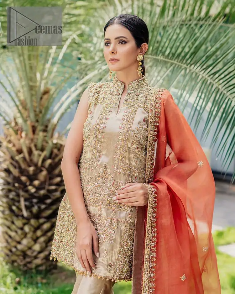 Envelop yourself into a dazzling love affair. The unique article in ivory colour just highlighted you at any event. The short shirt of the article is handsomely decorated with golden embroidery which includes kora, dabka, tilla, Kundan and Sitara work to make your event blazing and dazzling. It is enhanced with a collared neckline to make this outfit more formal when come with a sleeveless style. Further, it is coordinated with pant which is embellished with golden embroidery. Last but not least piece the dupatta comes in rust colour having four-sided embellished borders to encapsulate you in stars.