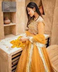 Mustard is just associated and boosts your Mehandi.  Presenting a dreamy mustard frock with a heavily embroidered bodice on a silver base. The bodice is further enhanced with handwork that includes crystal, tilla, kora and dabka work. Furthermore, the boat shape neckline and tiny work on full sleeves have the super style just to boost your day. The bottom is decorated with artistic embroidery that is adding glam to it. The Mehandi look is completed with an artistically crafted frilled lehenga which frill borders displaying the traditional hint of charm. It is coordinated with a dupatta in the same colour that is embellished with four-sided borders as well.