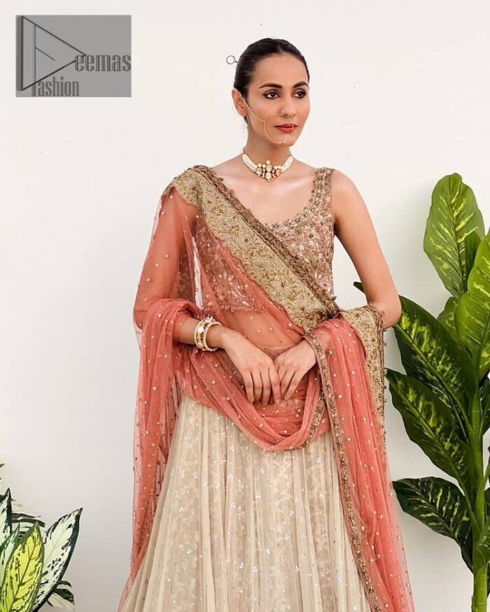 The perfect outfit for walima to enhance your glow. Starting this article with a dream rust blouse having a strap neckline and prominent sleeveless style to embrace the romantic culture. The following blouse is fully embellished with golden embroidery that is prominent with tilla, dabka, kora, pearls and sequins spray to fulfil your dreamy look. It is coordinated with an ivory can-can lehenga whose border is again rendered with golden embroidery and sequins sprayed all over to continue the look. Complete this outfit with a rust dupatta which is embellished with four-sided borders and sequins sprayed all over to enhance the glow of the bride.