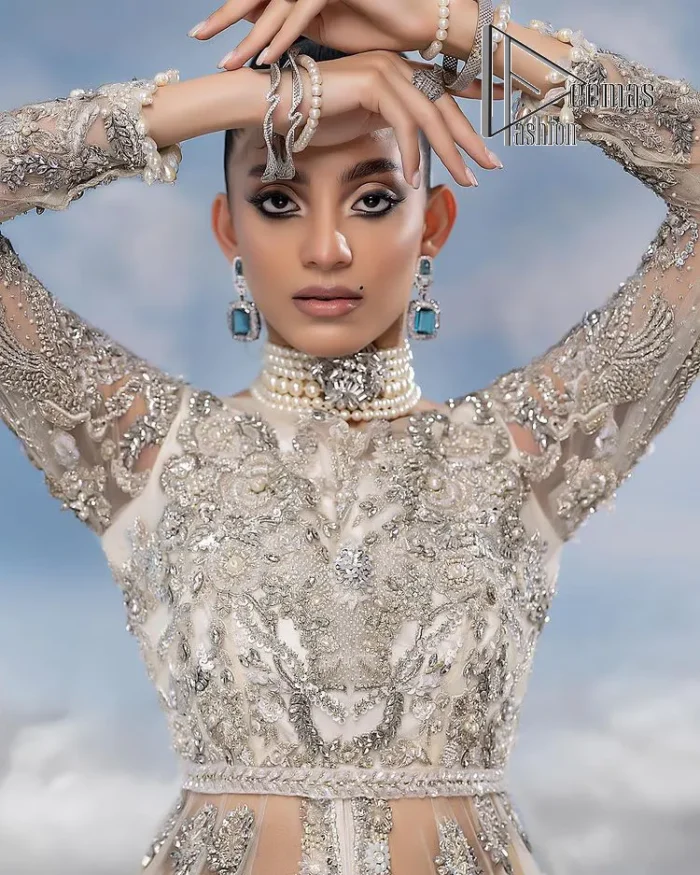 The mind wears the colours of the soul, as a beige of those of his master. Starting this nikah outfit with a beige frilled maxi which is laboriously hand-rendered with silver embroidery to fulfil the fairy dream of every bride. Furthermore, it is enhanced with tilla, dabka, kora and crystal which magnifies the beauty of this nikah outfit. The illusion neckline looks as amazing when comes with full sleeves as the moon with stars. The maxi of this nikah outfit is systemized with a lehenga in the same colour which is proof of uniqueness. Complete this nikah outfit with a dupatta in the same colour having a four-sided embellished border and sequins sprayed all over.    
