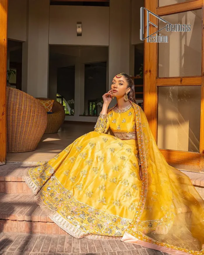 Yellow is just associated with mehndi as the sun is associated with brightness. DeemsFashion presents the bright yellow Pakistani mehndi outfit which laboriously begins with a blouse which is handsomely hand-rendered with silver and copper embroidery to make your day super duper bright. The boat shape neckline and full sleeves of this Pakistani mehndi outfit add to the breathtaking dream of the bride. It is paired up with a lehenga in the same colours which is adorned with floral motifs and bordered embroidery as well. Complete this Pakistani mehndi outfit with a dupatta in the same colour which is adorned with a four-sided embellished border and sequins sprayed all over.