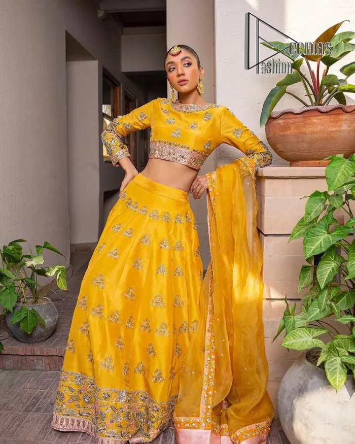 Yellow is just associated with mehndi as the sun is associated with brightness. DeemsFashion presents the bright yellow Pakistani mehndi outfit which laboriously begins with a blouse which is handsomely hand-rendered with silver and copper embroidery to make your day super duper bright. The boat shape neckline and full sleeves of this Pakistani mehndi outfit add to the breathtaking dream of the bride. It is paired up with a lehenga in the same colours which is adorned with floral motifs and bordered embroidery as well. Complete this Pakistani mehndi outfit with a dupatta in the same colour which is adorned with a four-sided embellished border and sequins sprayed all over.