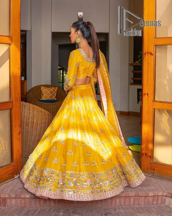 Yellow is just associated with mehndi as the sun is associated with brightness. DeemsFashion presents the bright yellow Pakistani mehndi outfit which laboriously begins with a blouse which is handsomely hand-rendered with silver and copper embroidery to make your day super duper bright. The boat shape neckline and full sleeves of this Pakistani mehndi outfit add to the breathtaking dream of the bride. It is paired up with a lehenga in the same colours which is adorned with floral motifs and bordered embroidery as well. Complete this Pakistani mehndi outfit with a dupatta in the same colour which is adorned with a four-sided embellished border and sequins sprayed all over.