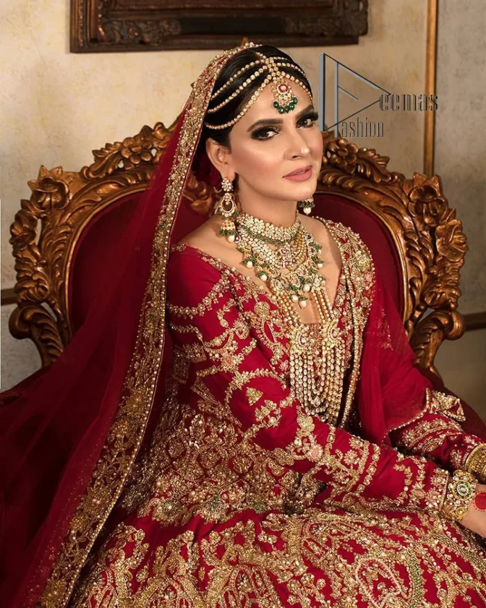 Happiness and confidence are the prettiest things that are associated with your wedding outfit. DeemasFashion presents this Pakistani reception wear in deep red colour. The deep red heavy maxi of this Pakistani reception wear is gorgeously adorned with a golden embroidery which is further enhanced with tilla, dabka, and kora. The boat shape neckline speaks of the boldness of the outfit. The following maxi is paired up with maroon sharara whose border is also embellished. Out and out of this Pakistani reception wears a dupatta in the same colour which is adorned with a four-sided border. Further, it is decorated with sequins sprayed all over.