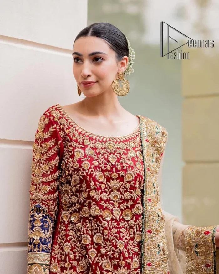 Embrace yourself with deep red on your big day. This deep red long shirt is meticulously hand-rendered with light golden embroidery which is further enhanced with tilla, dabka, kora and zardozi. The boat shape neckline of the long shirt is uniquely designed with full sleeves. This nikah wear is paired up with deep red sharara having embellished borders and ting floral motifs. Complete this nikah wear with a light fawn dupatta having four-sided embellished borders and tiny floral motifs all over to fulfil your dreams for your big day.