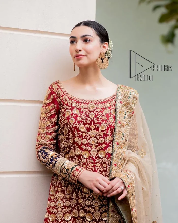 Embrace yourself with deep red on your big day. This deep red long shirt is meticulously hand-rendered with light golden embroidery which is further enhanced with tilla, dabka, kora and zardozi. The boat shape neckline of the long shirt is uniquely designed with full sleeves. This nikah wear is paired up with deep red sharara having embellished borders and ting floral motifs. Complete this nikah wear with a light fawn dupatta having four-sided embellished borders and tiny floral motifs all over to fulfil your dreams for your big day.