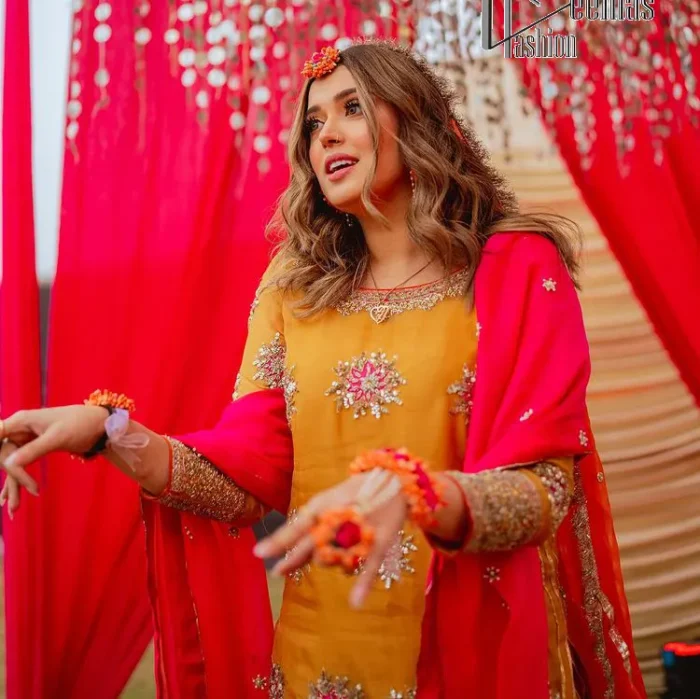 We seek outside the wonders we carry inside us. A mehndi dress in the mustard shirt is enhanced with gorgeous gota work. and is designed using the floral technique in pink and golden which is incrusted with tilla, dabka, kora and Sitara. The border of the mustard shirt is heavily ornamented with golden embroidery. The round neckline enhances the beauty of this mehndi dress when comes with three-quarter sleeves. It is paired up with mustard Gharara which is super simple and its border is encapsulated with Kiran. Complete this mehndi dress with a pink dupatta having ting floral motifs all over.