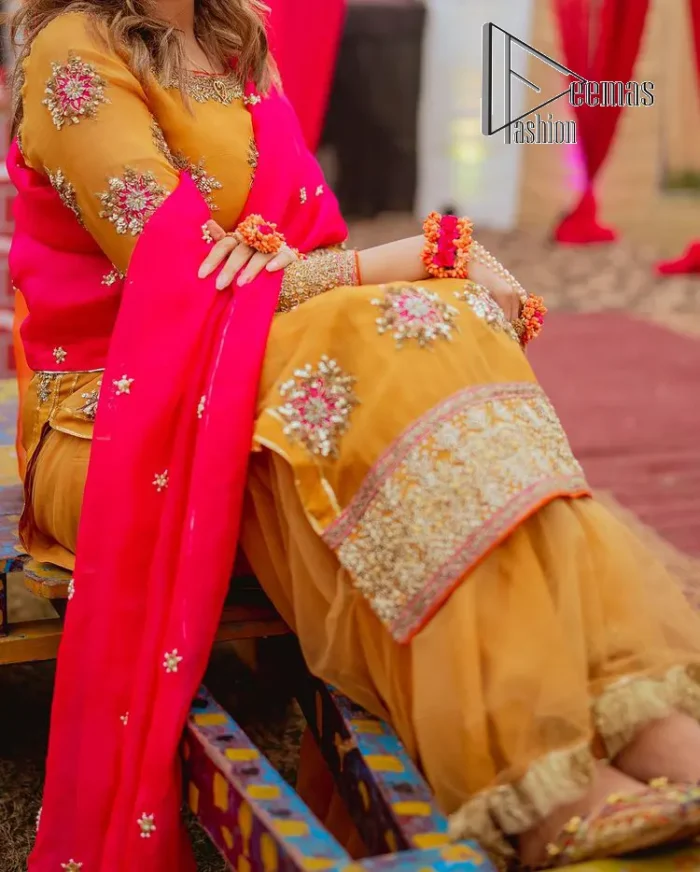 We seek outside the wonders we carry inside us. A mehndi dress in the mustard shirt is enhanced with gorgeous gota work. and is designed using the floral technique in pink and golden which is incrusted with tilla, dabka, kora and Sitara. The border of the mustard shirt is heavily ornamented with golden embroidery. The round neckline enhances the beauty of this mehndi dress when comes with three-quarter sleeves. It is paired up with mustard Gharara which is super simple and its border is encapsulated with Kiran. Complete this mehndi dress with a pink dupatta having ting floral motifs all over.