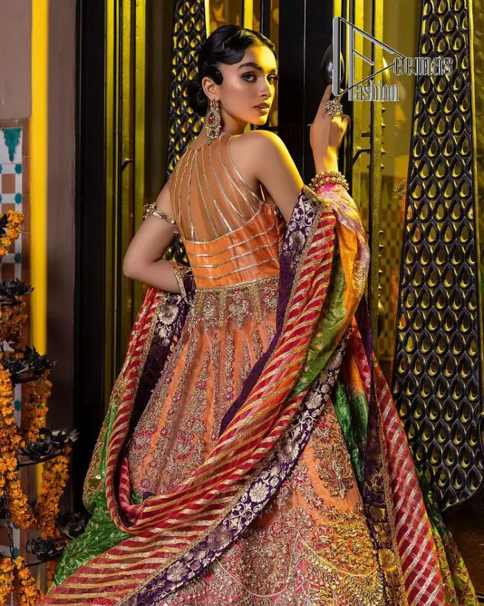 In a world full of trends, sometimes a bride just wants to wear something classic and traditional. In this way, DeemasFashion presents the major Pakistani walima dress which is nearest to the traditional style. The Pakistani walima dress starts from the orange pishwas which is beautifully styled with an illusion neckline and sleeveless. Further, it is enhanced with colourful embroidery which includes kora, dabka, tilla and Sitara to make your day super special. Pakistani walima dress is systemized with lehenga in the same colour but has a heavy green border to add beauty to the dress. Complete this Pakistani walima dress with a colourful dupatta to meet the following traditional trend.