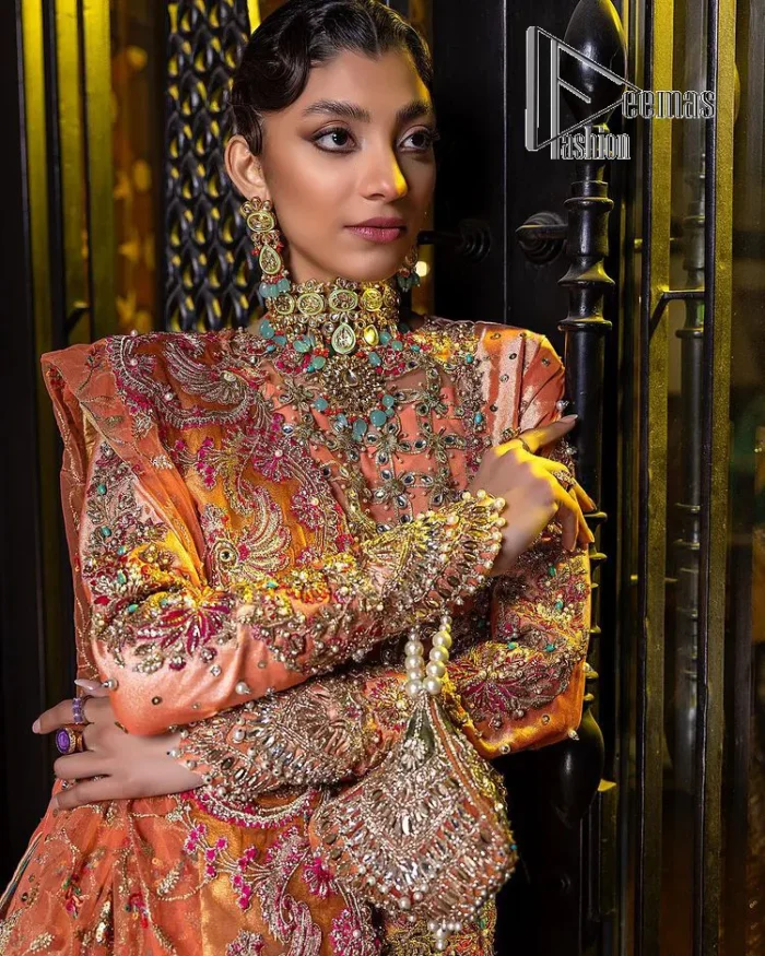 In a world full of trends, sometimes a bride just wants to wear something classic and traditional. In this way, DeemasFashion presents the major Pakistani walima dress which is nearest to the traditional style. The Pakistani walima dress starts from the orange pishwas which is beautifully styled with an illusion neckline and sleeveless. Further, it is enhanced with colourful embroidery which includes kora, dabka, tilla and Sitara to make your day super special. Pakistani walima dress is systemized with lehenga in the same colour but has a heavy green border to add beauty to the dress. Complete this Pakistani walima dress with a colourful dupatta to meet the following traditional trend.
