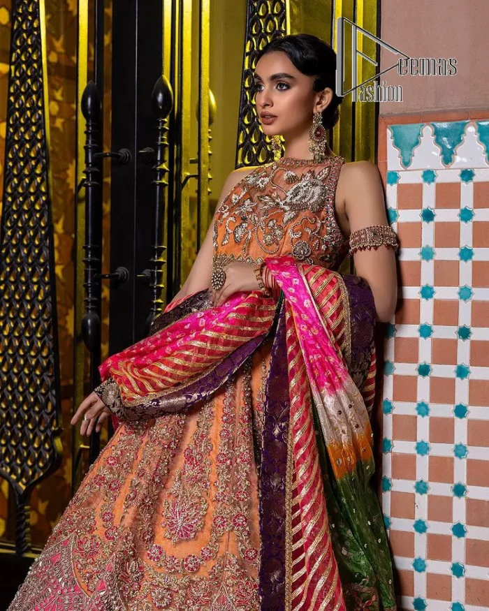 In a world full of trends, sometimes a bride just wants to wear something classic and traditional. In this way, DeemasFashion presents the major Pakistani walima dress which is nearest to the traditional style. The Pakistani walima dress starts from the orange pishwas which is beautifully styled with an illusion neckline and sleeveless. Further, it is enhanced with colourful embroidery which includes kora, dabka, tilla and Sitara to make your day super special. Pakistani walima dress is systemized with lehenga in the same colour but has a heavy green border to add beauty to the dress. Complete this Pakistani walima dress with a colourful dupatta to meet the following traditional trend.
