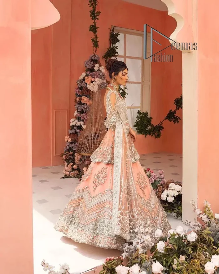 Feeling just peachy. DeemasFashion presents this peachy nikah outfit which begins with peplum in the peach colour. The following peplum is meticulously embellished with a silver embroidery which involves tilla, dabka, kora and Sitara. Further, the V shape neckline of the peplum looks as amazing as the embellished full sleeves. The Nikah outfit is coordinated with a fluffy lehenga having embellished borders and large floral motifs to make your day super peachy. Complete this nikah outfit with a dupatta which is adorned with four-sided embellished borders and floral motifs in the pattern.