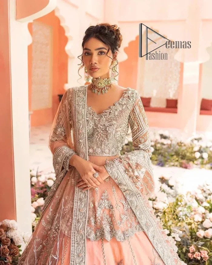 Feeling just peachy. DeemasFashion presents this peachy nikah outfit which begins with peplum in the peach colour. The following peplum is meticulously embellished with a silver embroidery which involves tilla, dabka, kora and Sitara. Further, the V shape neckline of the peplum looks as amazing as the embellished full sleeves. The Nikah outfit is coordinated with a fluffy lehenga having embellished borders and large floral motifs to make your day super peachy. Complete this nikah outfit with a dupatta which is adorned with four-sided embellished borders and floral motifs in the pattern.