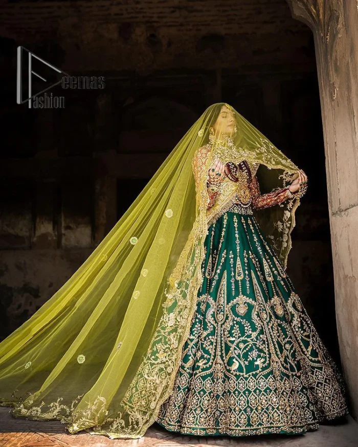 The blushing moment you found your dream mehndi outfit. This mehndi outfit is handsomely and attractively prepared in the level of contrast. Starting this mehndi outfit with a red blouse which is laboriously hand-rendered with light golden embroidery having tilla, kora, dabka and zardozi. In addition to this, it is enhanced with full sleeves and boat shape neckline to make your day super blush. The mehndi outfit is coordinated with a bottle green lehenga which is heavily ornamented with golden embroidery. Complete this article with a golden dupatta having Kiran on all sides. 