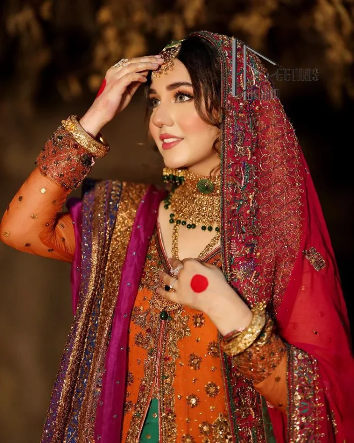 A colourful mehndi outfit is a power which directly influences the soul. Begin this mehndi outfit with a rusted front open shirt which is beautifully decorated with colourful embroidery to give you more power on your mehndi day. It is prominent with tilla, dabka, kora and zardozi. Further, the V shape neckline adds to this mehndi outfit when comes with full sleeves. Paired with a green lehenga having multiple colour borders to give you a more traditional look also. Complete this mehndi outfit with a colourful dupatta which is adorned with four-sided borders and sequins sprayed all over.