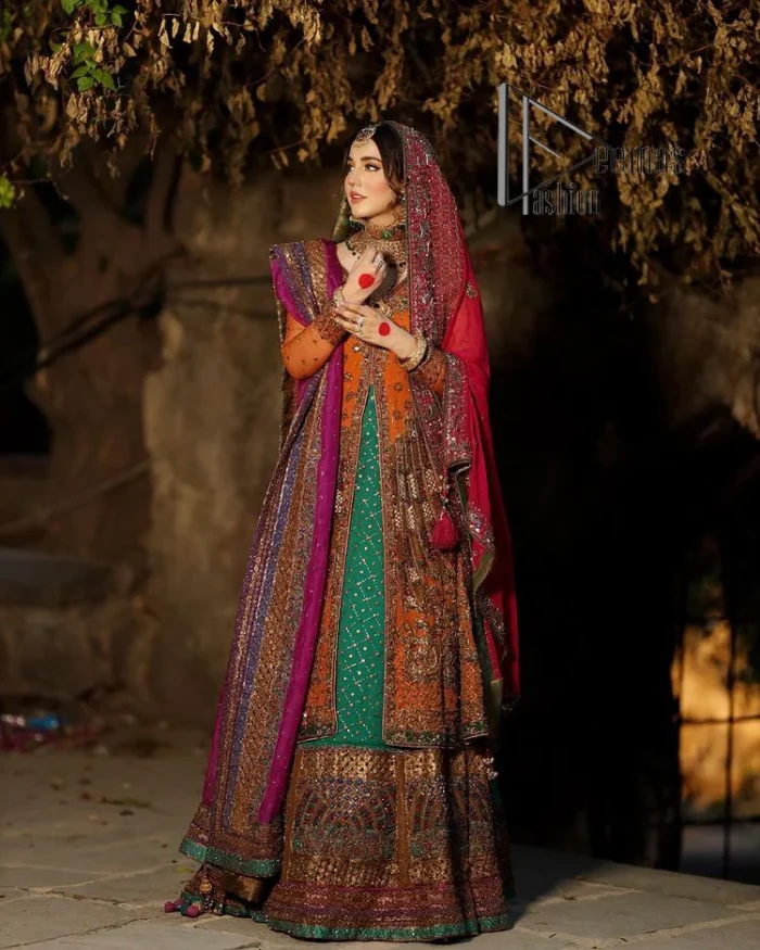 A colourful mehndi outfit is a power which directly influences the soul. Begin this mehndi outfit with a rusted front open shirt which is beautifully decorated with colourful embroidery to give you more power on your mehndi day. It is prominent with tilla, dabka, kora and zardozi. Further, the V shape neckline adds to this mehndi outfit when comes with full sleeves. Paired with a green lehenga having multiple colour borders to give you a more traditional look also. Complete this mehndi outfit with a colourful dupatta which is adorned with four-sided borders and sequins sprayed all over.