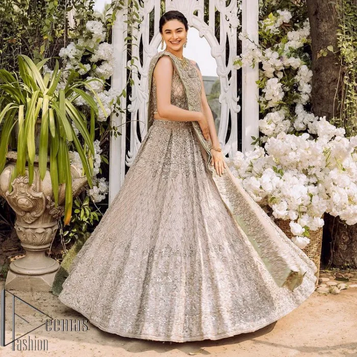 Go with tea rose on your Big day. DeemasFashion presents tea rose nikah wear to fulfil your dreamy look. The blouse in the tea rose colour is heavily ornamented with silver embroidery that enhances with tilla, dabka, kora and zardozi. Further, It is detailed with a round neckline and finished with a sleeveless style. The nikah wear is paired up with can-can lehenga which is heavily embellished to make you the spotlight among all. Complete this article with a dupatta which is enhanced with four-sided embellished borders and sequins sprayed all over to make your day more memorable and attractive.