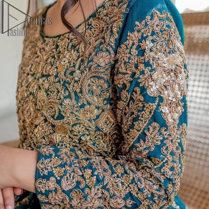 The bride wears blue just touches the blues of the sky. DeemasFashion introduces this teal blue mehndi outfit which begins with panelled Anarkali. The following Anarkali is exquisitely hand-rendered with a light golden embroidery which involves tilla, dabka, kora and zardozi. The floral motifs are also embellished on panels to make this Anarkali priceless. Furthermore, the round shape neckline and full sleeves also enhance the beauty of this mehndi outfit. It is handsomely and attractively paired up with brocade lehenga which gives a unique pieace of charmless.