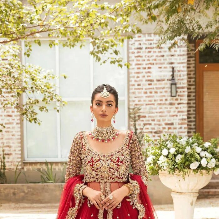 Vibrant outfit to make your reception day more shiny and bright. DeemasFashion presents this maxi in deep red colour, featuring golden embroidery which is enhanced with tilla, dabka, kora, naqshi, zardozi and the magic of Resham. The following scalloped front open maxi has a Round neckline to meet the traditional look when comes with three-quarter sleeves.  In addition to this, it is paired up with a back train lehenga in the same colour framed with embroidery on the border. Complete this article with a scalloped dupatta which is adorned with four-sided borders and sequins sprayed all over for sun-kissed splendour!