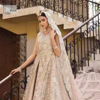 The subtle colour palette, delicate embroidery and eye-catching details. All in all a true style statement! Presenting this light brown maxi which is a luxuriously encrusted masterpiece is laden with tilla, dabka kora, stones,  and delicate Resham. The following front open scalloped maxi is adorned with silver embroidery to make your Nikah day remarkable. The embellished neckline along with the sleeveless style makes you a pretty and unique bride ever. Paired up this article with a sharara whose border is adorned with embroidery. Finish this outfit with a dupatta, framed with four-sided borders and sequins sprayed all over for attractiveness and marvellous details.