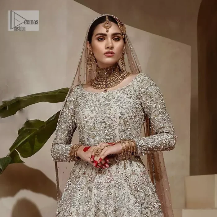 Walk with style on your Nikah day and let the flare follow! This light fawn flare maxi is decorated with tilla, dabka, kora, Kundan and details of Zardozi and enhanced with light golden embroidery for a unique artistic look. Further, the boat shape neckline also intensified the beauty of the outfit when comes with full sleeves. It is coordinated with flare lehenga in the same colour having border embellished to make your day booster day. Complete this outfit with a dupatta, framed with a four sided embellished border and sequins sprayed all over.